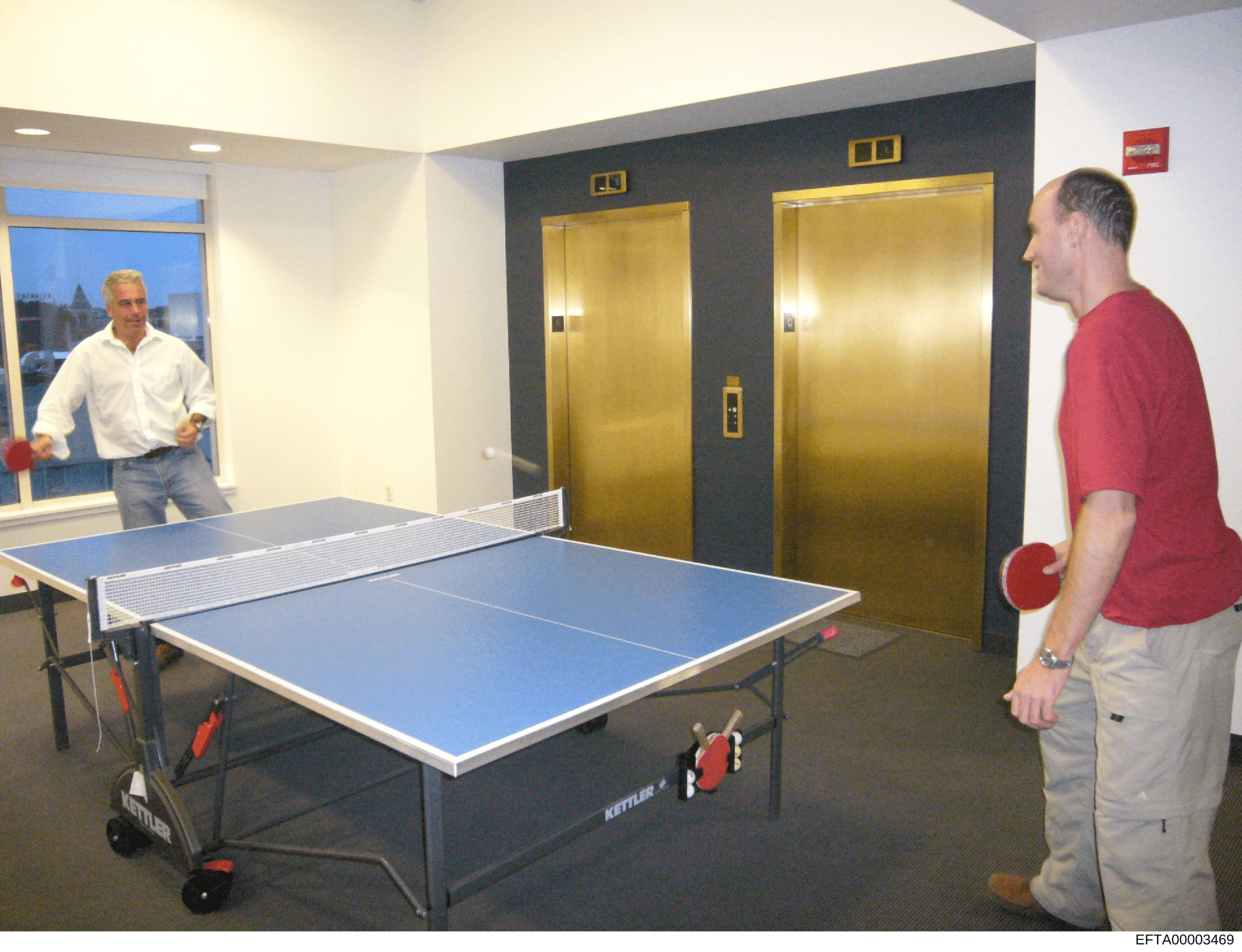 This photograph shows an interior space within what appears to be a residential or commercial building, featuring a ping pong table in active use. Two men are visible playing table tennis in a modern room with contemporary furnishings, including gold