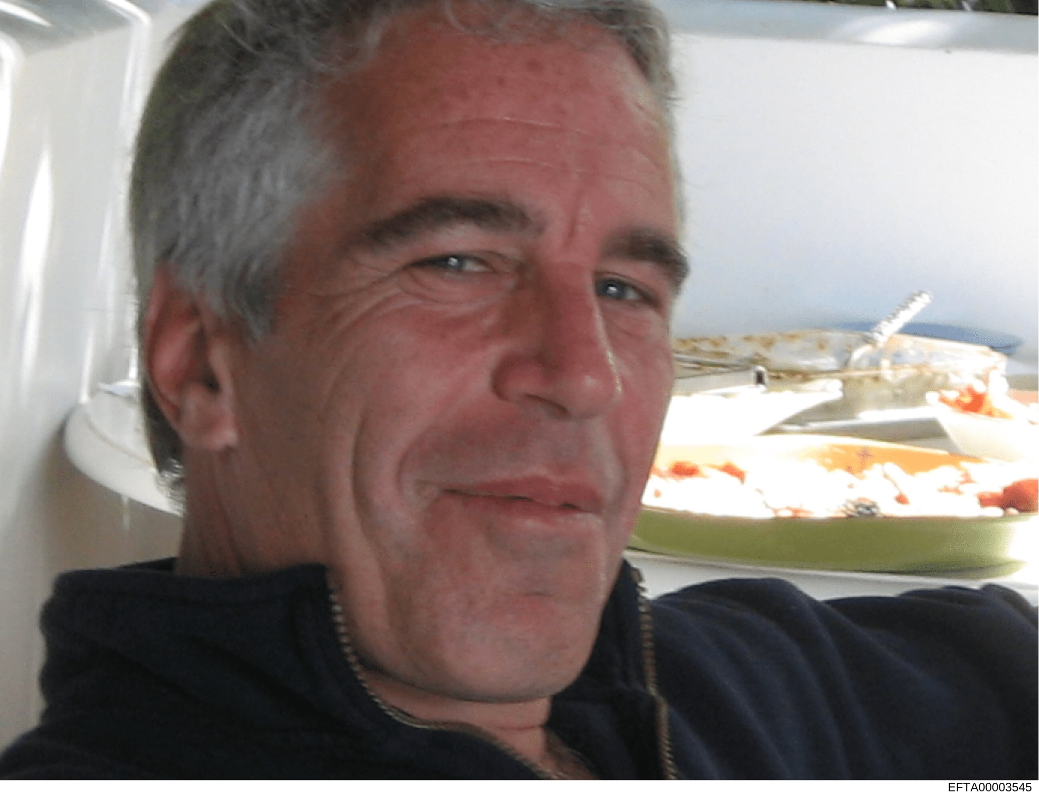 This is a photograph of a middle-aged male subject taken outdoors on what appears to be a boat or marine vessel. The image shows the subject in close-up, with water and another vessel visible in the background. The photo is catalogued as evidence in