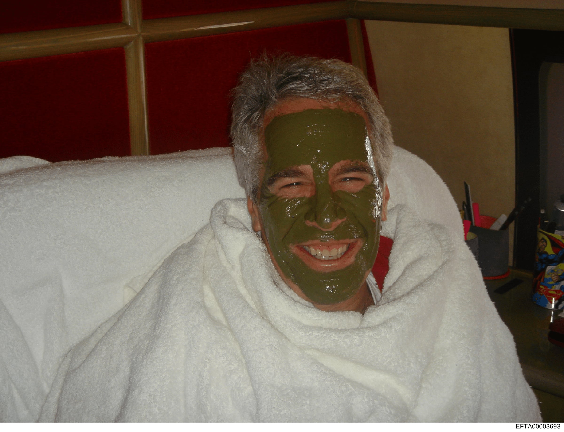 This is a personal photograph showing an unidentified male with a green facial mask applied, sitting on a white couch or chair. The image appears to be a casual domestic setting photo, likely taken for personal or recreational purposes. Its inclusion