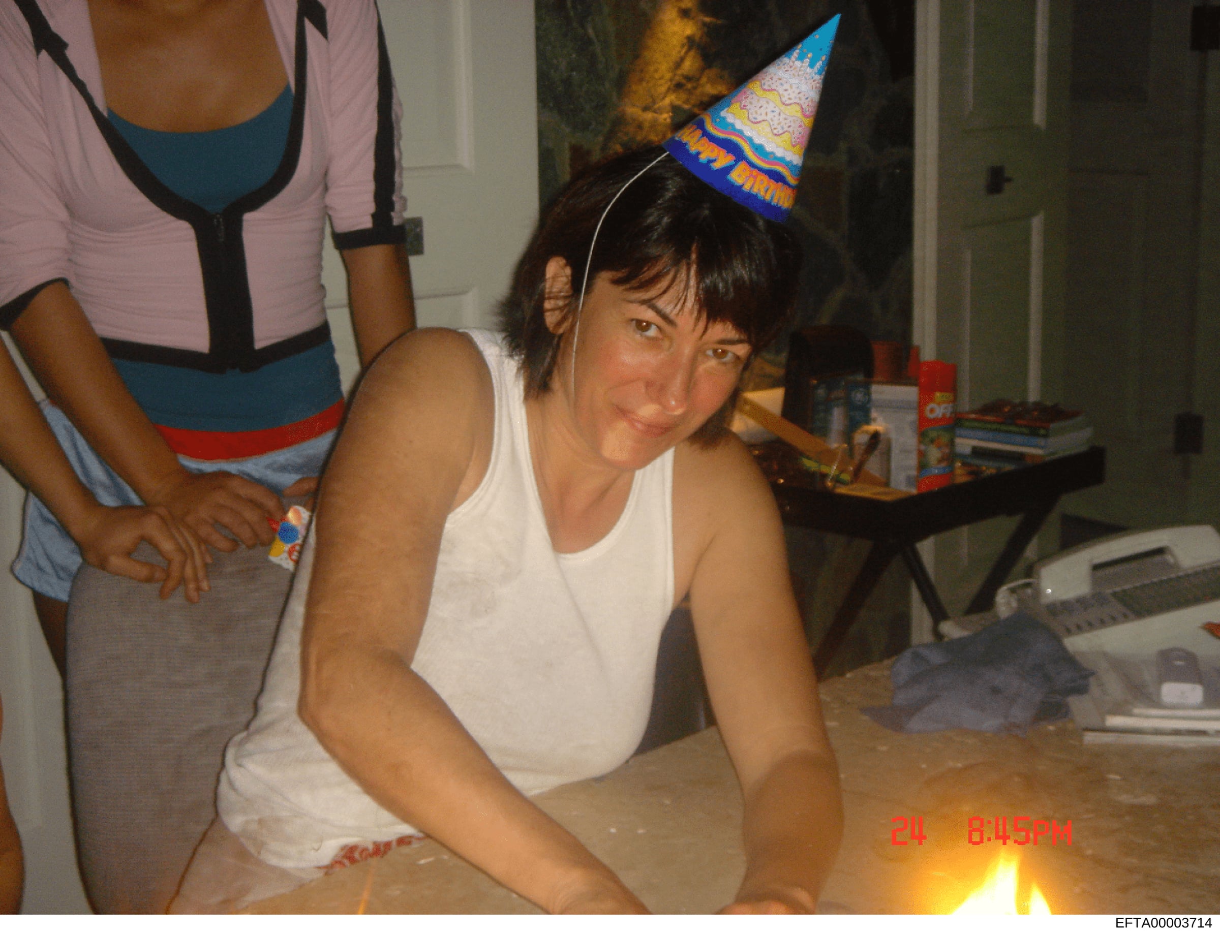 This is a personal photograph showing a woman at what appears to be an indoor birthday celebration wearing a party hat. The image is dated August 24, 2004 based on the timestamp visible in the photo. The photograph was recovered as part of the invest