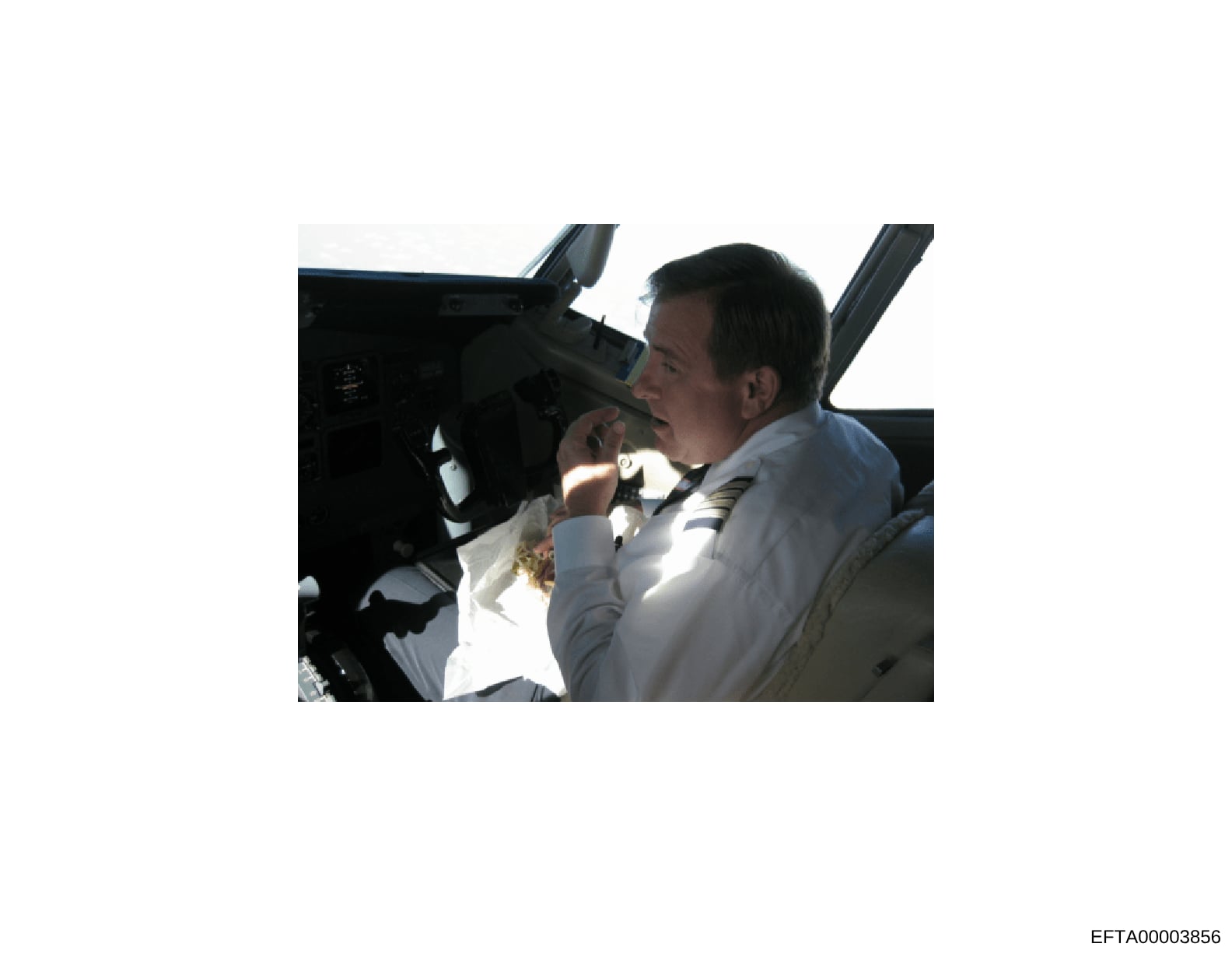 This is a photograph showing a man in the cockpit of an aircraft, appearing to be at the controls or operating equipment. The image shows the interior of what appears to be a private aircraft with visible cockpit instrumentation. The photo is evidenc