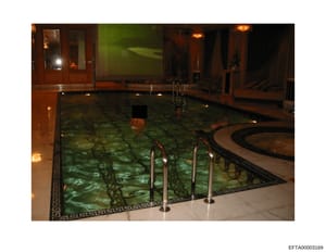 This is an evidence photograph showing an indoor swimming pool facility with multiple individuals in the water. The image captures the pool's interior design, lighting, and architectural features, and appears to be documentation of a residential or p
