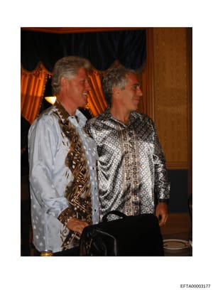 This is a photograph of two middle-aged men at what appears to be an indoor social gathering or event in an elegant interior setting. The men are standing together in profile, wearing formal attire with patterned shirts and decorative ties. The backg