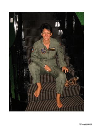 This is a photograph showing a person wearing a U.S. Air Force flight suit with visible patches and insignia, seated inside what appears to be a military aircraft cabin with striped seating. The photo is undated but appears to be from the 1980s or 19