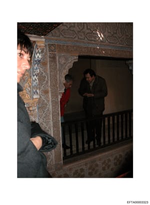 This is an evidence photograph showing the interior of an elaborately decorated space with ornamental wall panels featuring intricate geometric and floral patterns in gold, blue, and brown tones. The image captures at least three people in the room, 