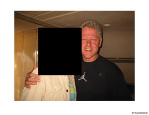 This is an evidence photograph from the Epstein investigation files showing an indoor scene with two individuals. One person is visible on the right side of the frame wearing a black Jordan-branded shirt, smiling at the camera. The other person on th