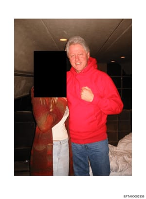 This is a photograph showing a man with gray hair wearing a bright red hoodie and blue jeans posing indoors next to another person whose face and upper body have been redacted with a black rectangle. The setting appears to be inside a residential or 