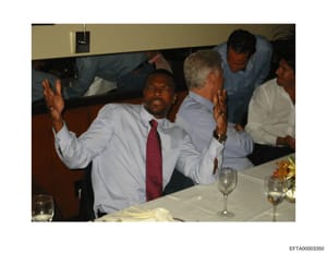 This photograph depicts an indoor social gathering or event, likely a formal dinner or reception, showing multiple men in business attire engaged in conversation. The image appears to be from the Epstein investigation files and may document social in