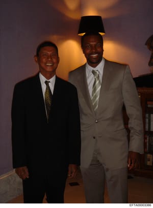 This is a photograph showing two men in business suits posing together indoors at what appears to be a formal event or gathering. The image is undated and the identities of the individuals are not explicitly stated in the document. The photo was incl