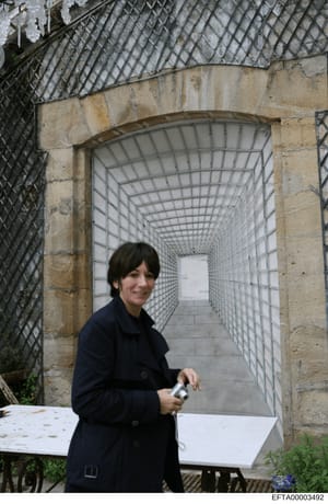 This is a photograph showing a woman in a dark navy jacket standing at the entrance of a long, white tile-lined tunnel or interior passageway. The image appears to be a casual personal photograph rather than official investigation documentation. The 