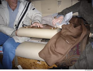 This photograph documents an interior inspection or appraisal of a property, showing two individuals examining fabric samples and furnishings, likely as part of an asset inventory or property assessment. The image captures what appears to be a formal