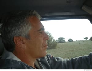 This is a candid photograph taken inside a vehicle showing a middle-aged man with gray hair in profile view looking out the window. The image captures a rural landscape with fields and trees visible through the vehicle window. The photograph appears 