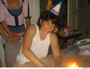 This is a personal photograph showing a woman at what appears to be an indoor birthday celebration wearing a party hat. The image is dated August 24, 2004 based on the timestamp visible in the photo. The photograph was recovered as part of the invest