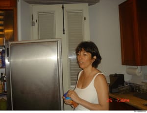 This is a photograph taken in a residential kitchen showing a woman in a white tank top standing near a refrigerator. The image is dated 25th at 7:36 PM based on the timestamp visible in the lower right corner. The kitchen contains standard appliance