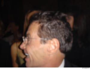 This is a profile photograph showing a man wearing clear-framed glasses, captured from the side against a dark background. The image appears to be an evidentiary or identification photo from the investigation files, though the subject's identity is n