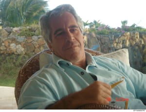 This is a personal photograph showing Jeffrey Epstein seated outdoors at what appears to be one of his properties. The image depicts him in casual attire at a Mediterranean-style residence with stone walls, palm trees, and flowering plants visible in