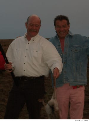 This is a personal photograph showing two men posing together indoors. The image appears to be from investigative files and may be used as documentary evidence. Without identifying information visible on the photo itself, the context of its inclusion