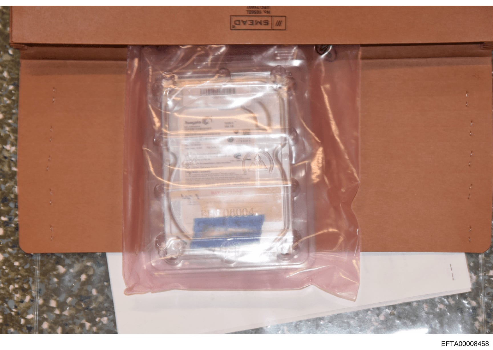 This is an evidence photograph showing a sealed, labeled plastic storage container with what appears to be multiple stacked documents or records inside. The container bears official markings and is photographed as part of the investigation file docum