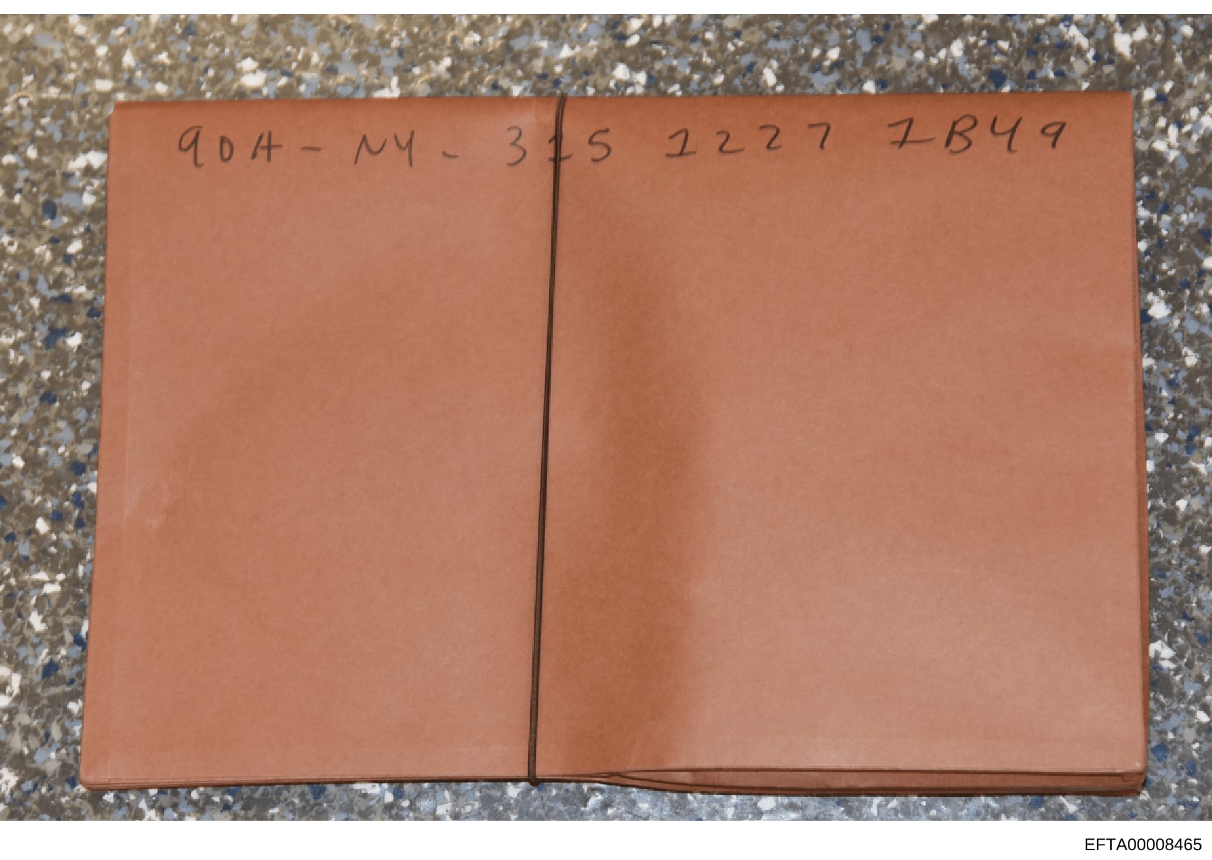 This is a photograph of a sealed tan or rust-colored folder or envelope with handwritten markings on the cover. The visible notation reads '904-NY-3/5 2227 7B49,' which appears to be a case reference, location code, and identification number. The fol