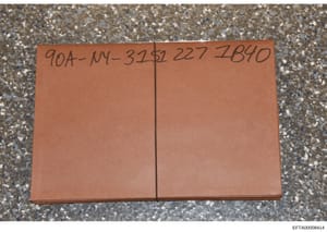 This is a photograph of a closed orange or tan-colored folder or binder placed on a textured surface. The folder has a handwritten reference number visible on its spine or cover (90A-NY-3252 227 IB4D). The image appears to be evidence documentation, 