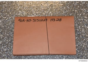 This photograph shows a terracotta-colored evidence container or folder marked with a handwritten case reference number (90A-NY-315/1227) and evidence identifier (IB28). The container is photographed on a speckled concrete surface. This appears to be
