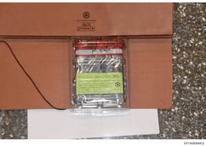 This is a forensic evidence photograph showing a sealed hard drive in a clear plastic case with a red and white evidence tape and a yellow chain of custody label. The label indicates this is a 1000 GB Seagate hard drive (SN ST1000NM0011) that was sei