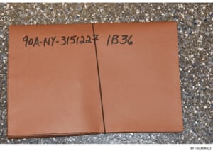 This photograph documents a terracotta/orange-colored file folder or evidence container bearing handwritten reference numbers '90A-NY-3/51/22' and 'IB36'. The markings suggest this is physical evidence from the investigation that has been catalogued 