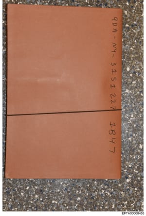 This is a photograph of a tan/rust-colored envelope or document cover with handwritten notations on both sides. The visible text appears to include case reference numbers or identifiers written in pen. The envelope is photographed against a terrazzo 