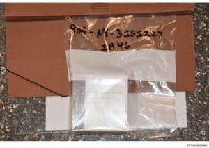 This is a photograph of an evidence bag or container used in the Epstein investigation. The bag appears to be a clear plastic evidence envelope with a brown cardboard backing, labeled with handwritten markings including what appears to be item number
