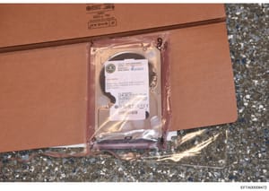 This is a photograph of a hard drive that has been seized as evidence and labeled by law enforcement. The drive is packaged in an anti-static bag and affixed with an FBI evidence label indicating it contains a master copy of DVR 2 controller images, 